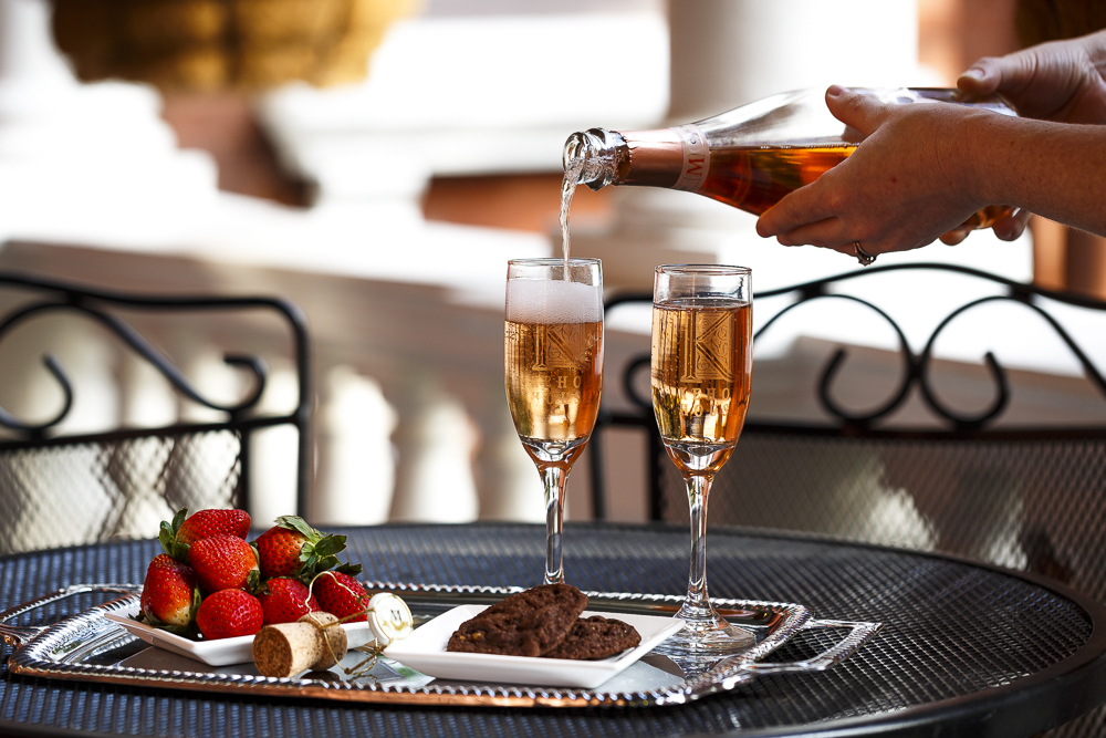Waiter Pouring Two Glasses of Champagne Served with a Side of Strawberries